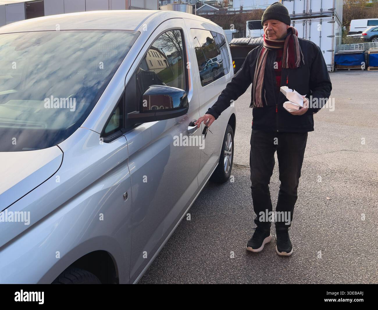 Aktive Alltagsmobilität Seniorenleben mit einem älteren Mann, der bei Tageslicht draußen eine Autotür öffnet, Lebensmittel beim Kauf mitnimmt und unabhängig bleibt Stockfoto