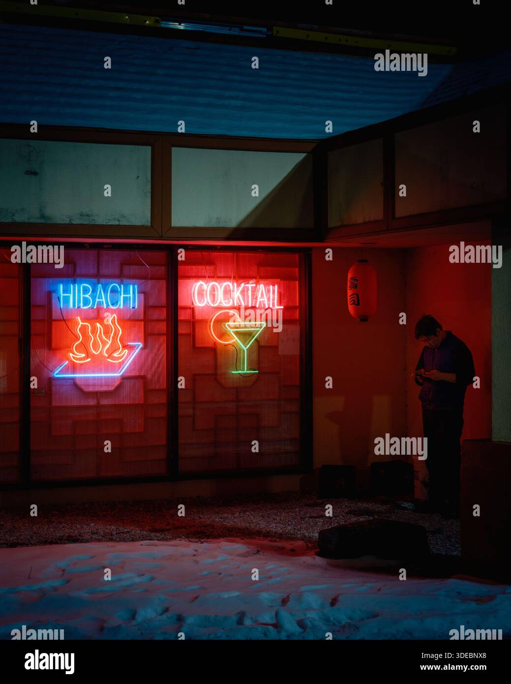 In der schwach beleuchteten Straßenszene gibt es Neonschilder für Hibachi und Cocktails. Eine Person steht in der Nähe bei der Tokyo Asian Cuisine in West Springfield, Mass Stockfoto
