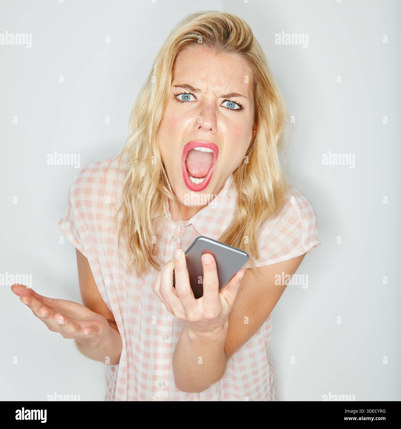 Wütende Frau, Porträt und Schreien mit Lautsprechertelefon im Studio für Kampf auf weißem Hintergrund. Weibliche Person, Model oder Schreie mit Handy Stockfoto