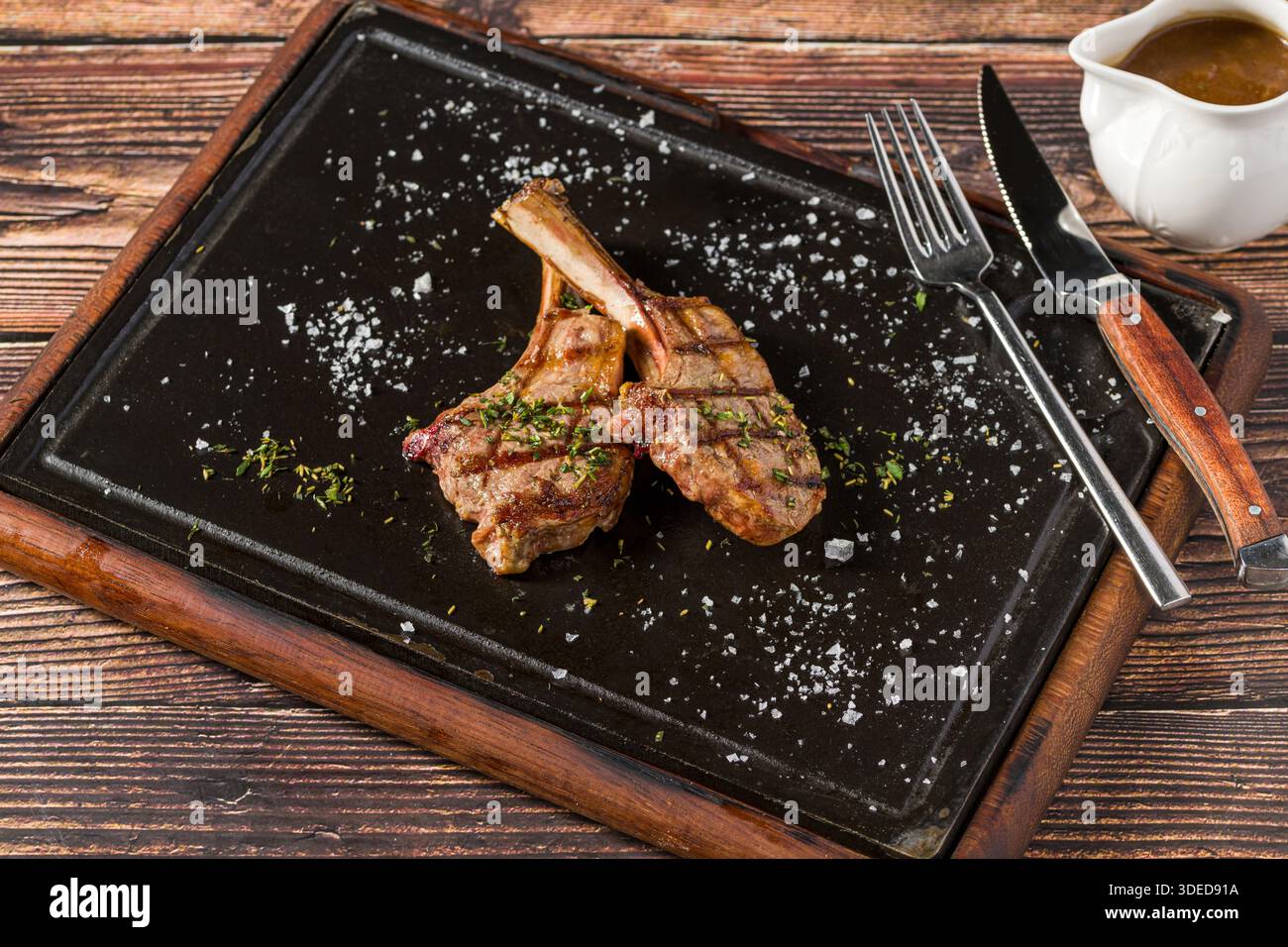 Gegrillte Lammkoteletts auf schwarzem Steinteller Stockfoto