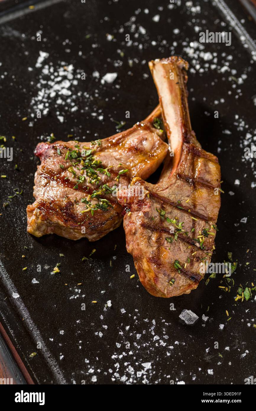 Gegrillte Lammkoteletts auf schwarzem Steinteller Stockfoto