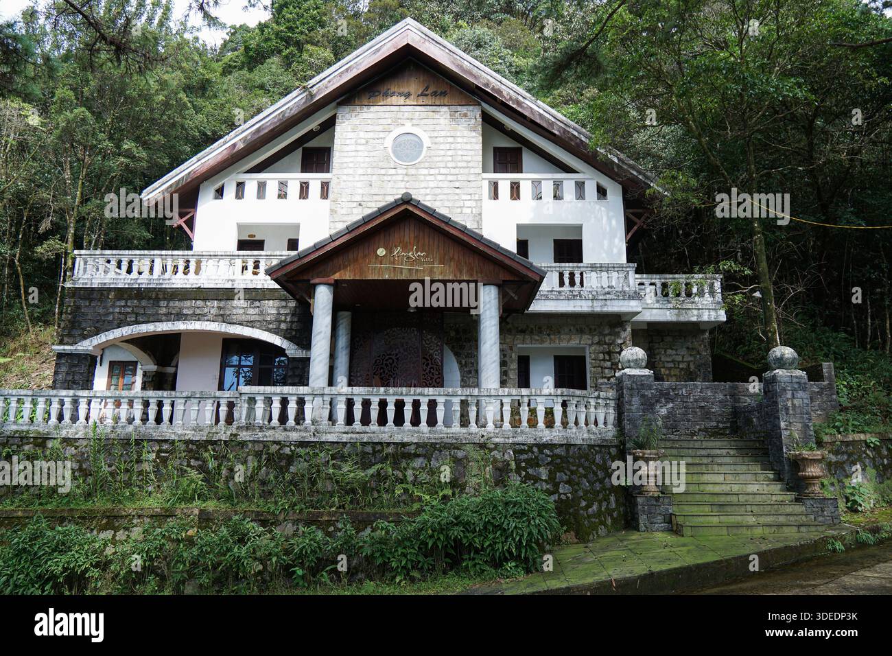 Charmante Phong Lan Villa in einem üppigen vietnamesischen Bergwald mit schöner Steinarchitektur und einladenden Balkonen für einen ruhigen Rückzugsort. Stockfoto