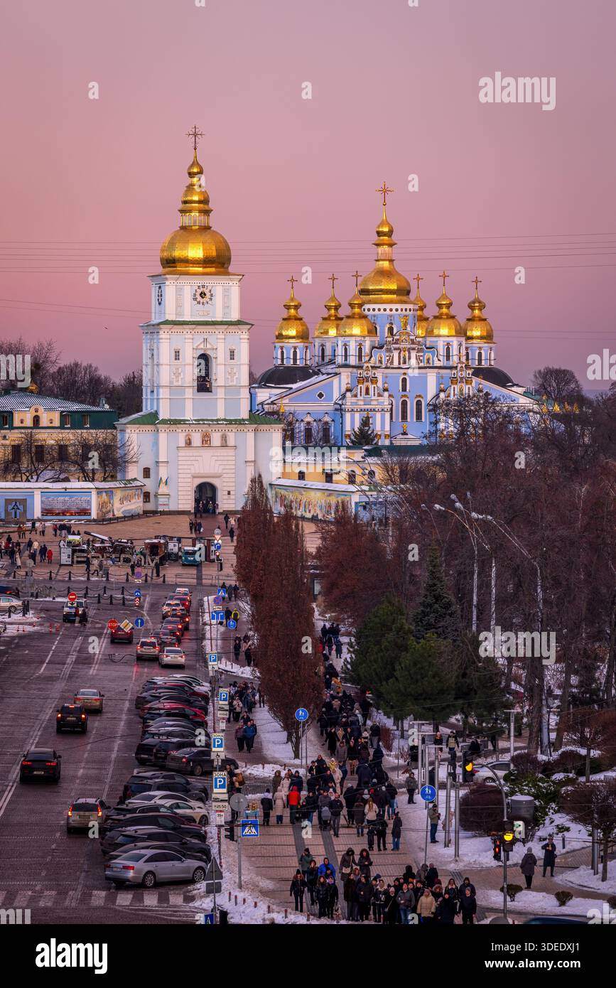 Panoramablick auf den Sofia-Platz in Kiew nach Sonnenuntergang, den rosa Winterhimmel, der über der Stadt leuchtet, und das Kloster St. Michaels mit der goldenen Kuppel in der Ferne. Stockfoto