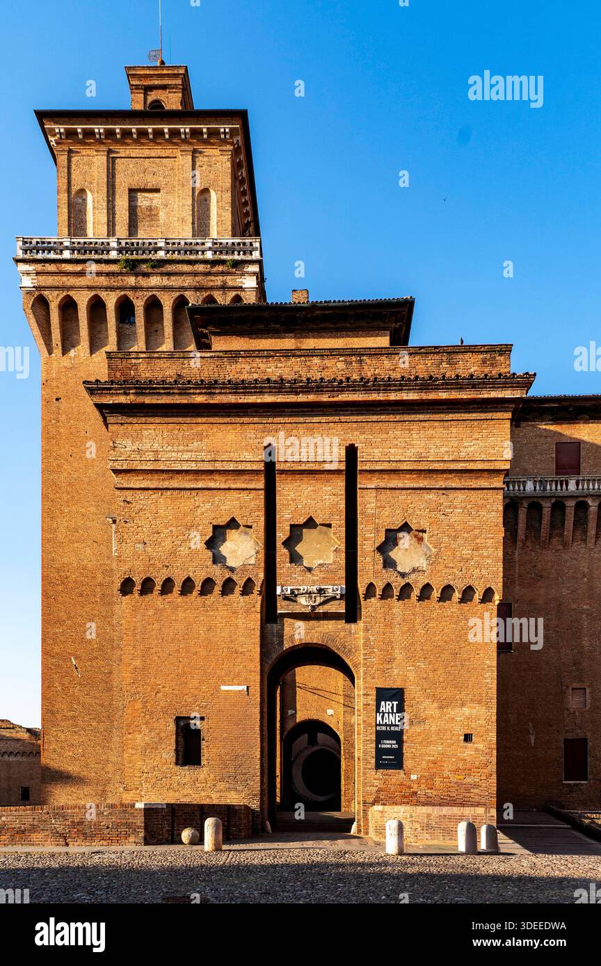 Ein historisches Backsteingebäude mit einem hohen Turm mit kunstvollen architektonischen Details und einem klaren blauen Himmel Stockfoto