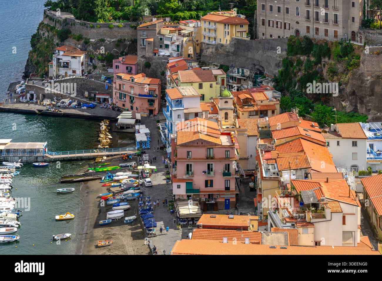Blick hinunter auf die Küste von Sorrent. Der Strand ist gesäumt von Touristen, Restaurants und farbenfrohen Häusern sowie Booten und Yachten am Yachthafen Via del Mare. Stockfoto