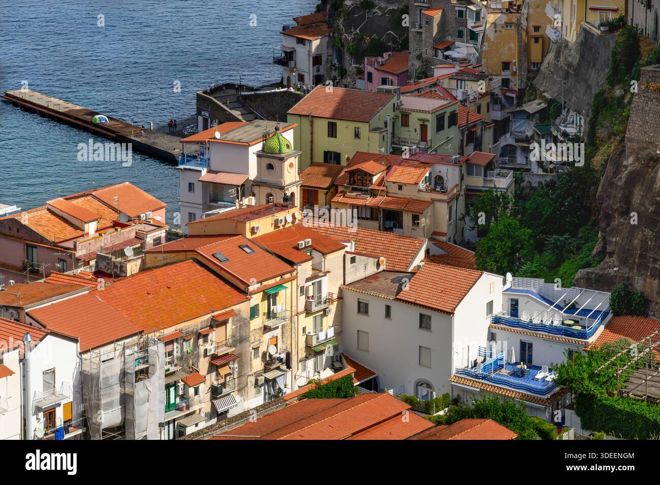 Blick hinunter auf die Küste von Sorrent. Der Strand ist gesäumt von Touristen, Restaurants und farbenfrohen Häusern sowie Booten und Yachten am Yachthafen Via del Mare. Stockfoto