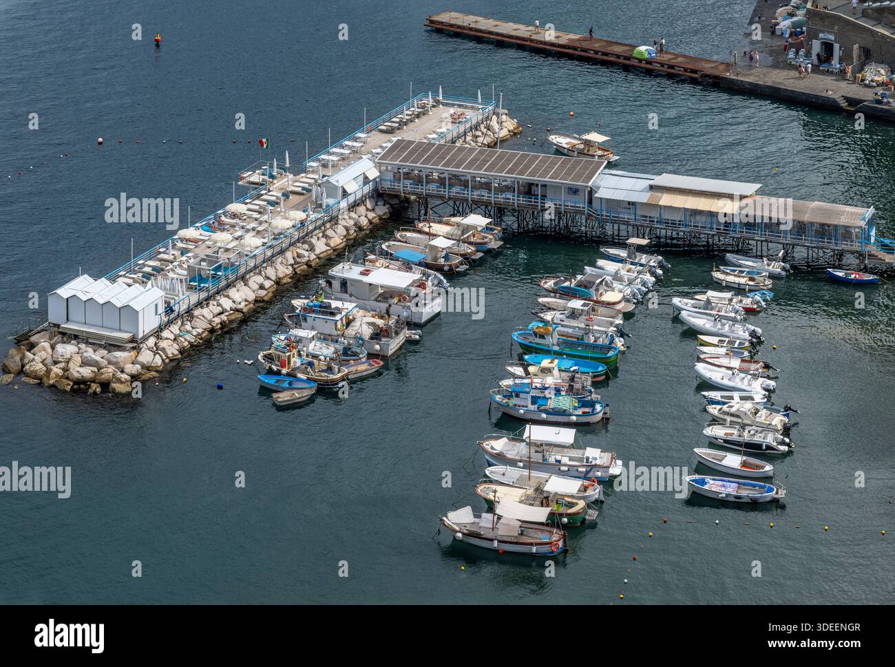 Blick hinunter auf die Küste von Sorrent. Der Strand ist gesäumt von Touristen, Restaurants und farbenfrohen Häusern sowie Booten und Yachten am Yachthafen Via del Mare. Stockfoto