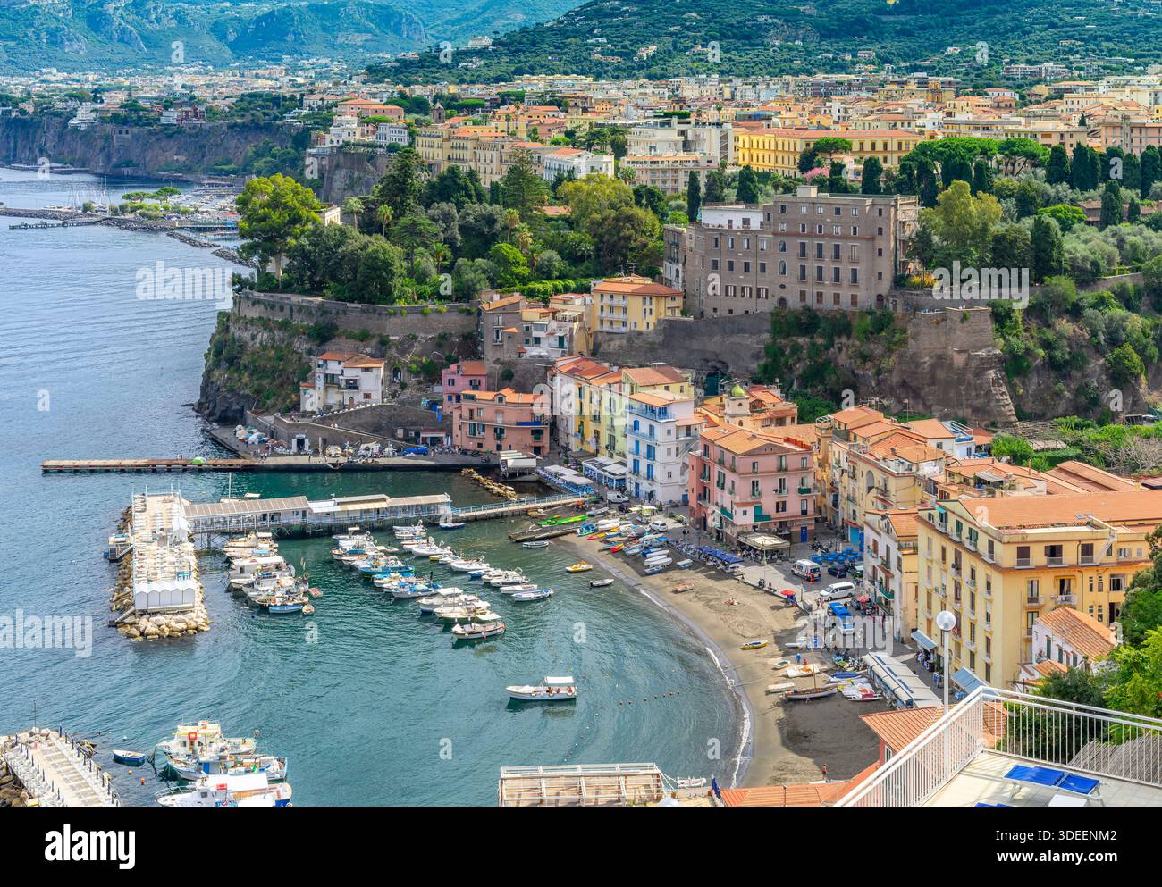 Blick hinunter auf die Küste von Sorrent. Der Strand ist gesäumt von Touristen, Restaurants und farbenfrohen Häusern sowie Booten und Yachten am Yachthafen Via del Mare. Stockfoto