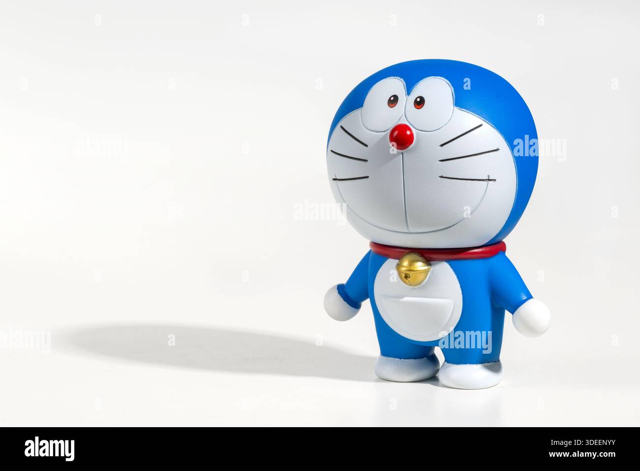 Blau-weiße Doraemon-Figur, die auf weißem Hintergrund steht und einen Schatten wirft Stockfoto