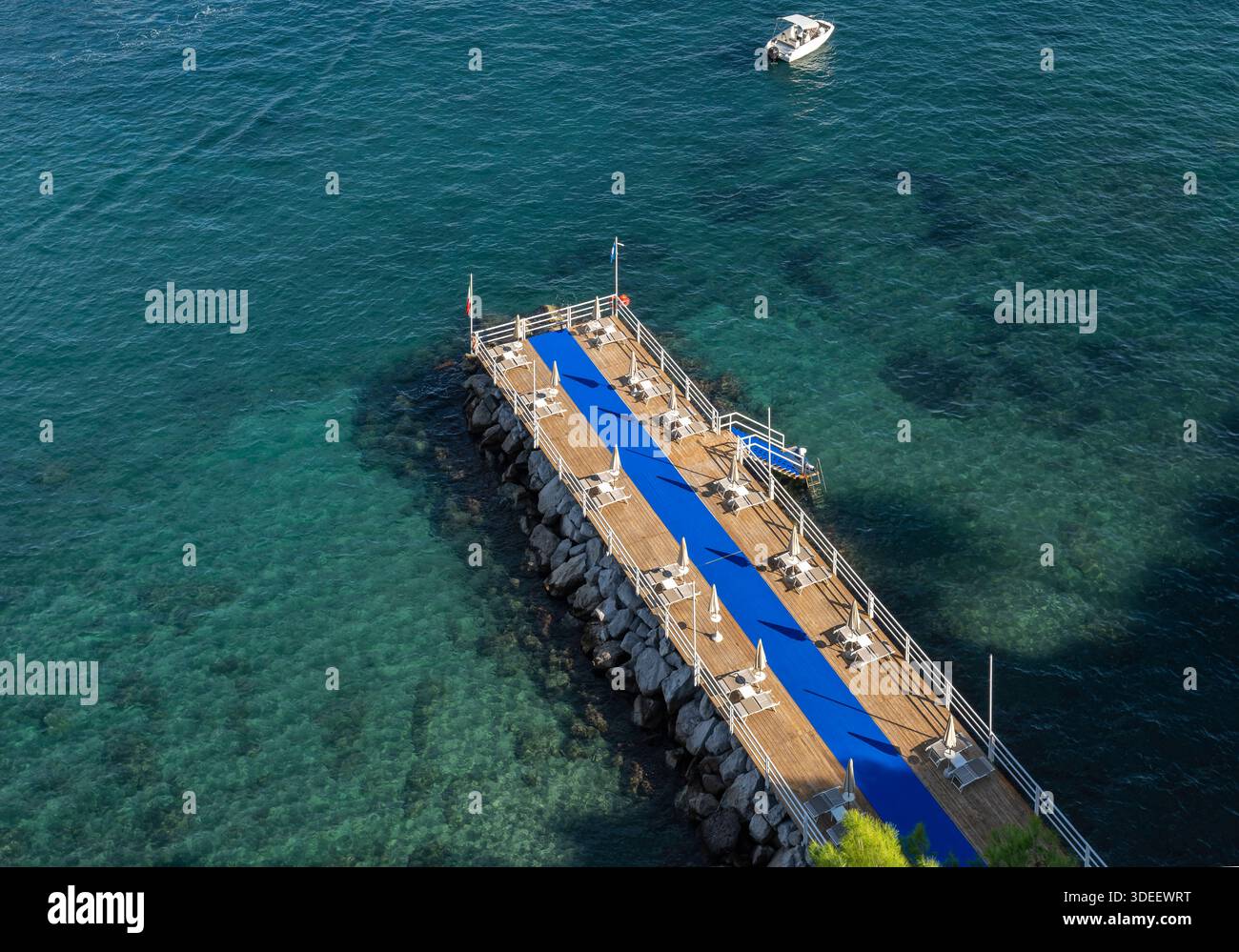 Blick hinunter auf den privaten Bereich von Sorrent am Meer Bagni Salvatore. Mit Touristen, Liegestühlen, Sonnenschirmen, Badehütten, Ruderbooten und Kajaks. Stockfoto