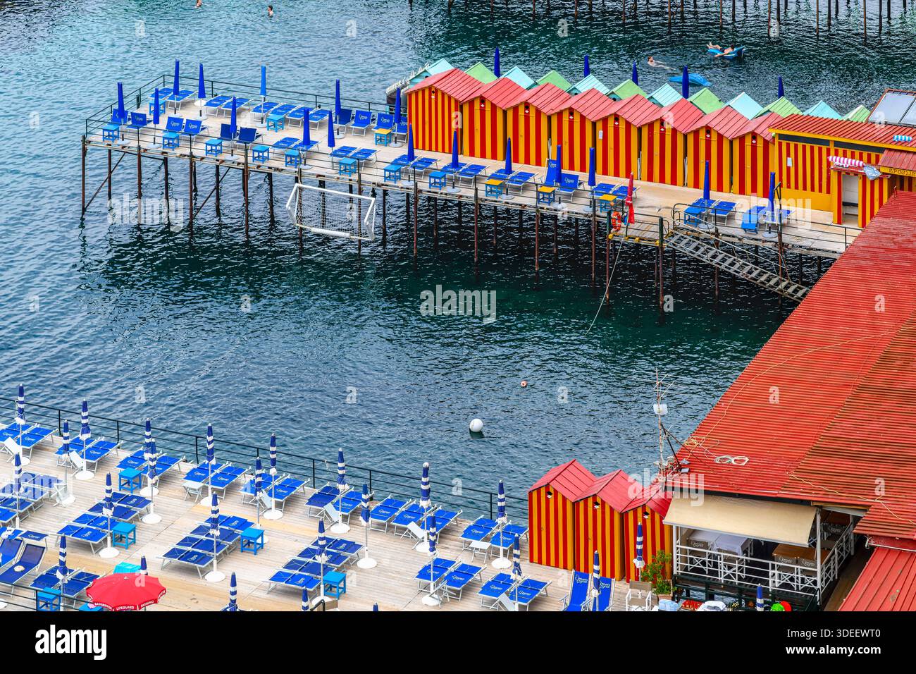 Blick hinunter auf den privaten Bereich von Sorrent am Meer Bagni Salvatore. Mit Touristen, Liegestühlen, Sonnenschirmen, Badehütten, Ruderbooten und Kajaks. Stockfoto