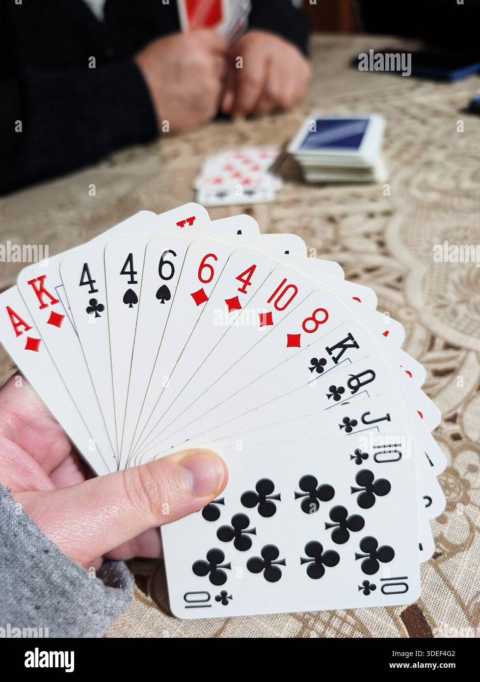 Nahaufnahme einer Person, die an einem Tisch sitzt und ein Kartenspiel spielt Stockfoto