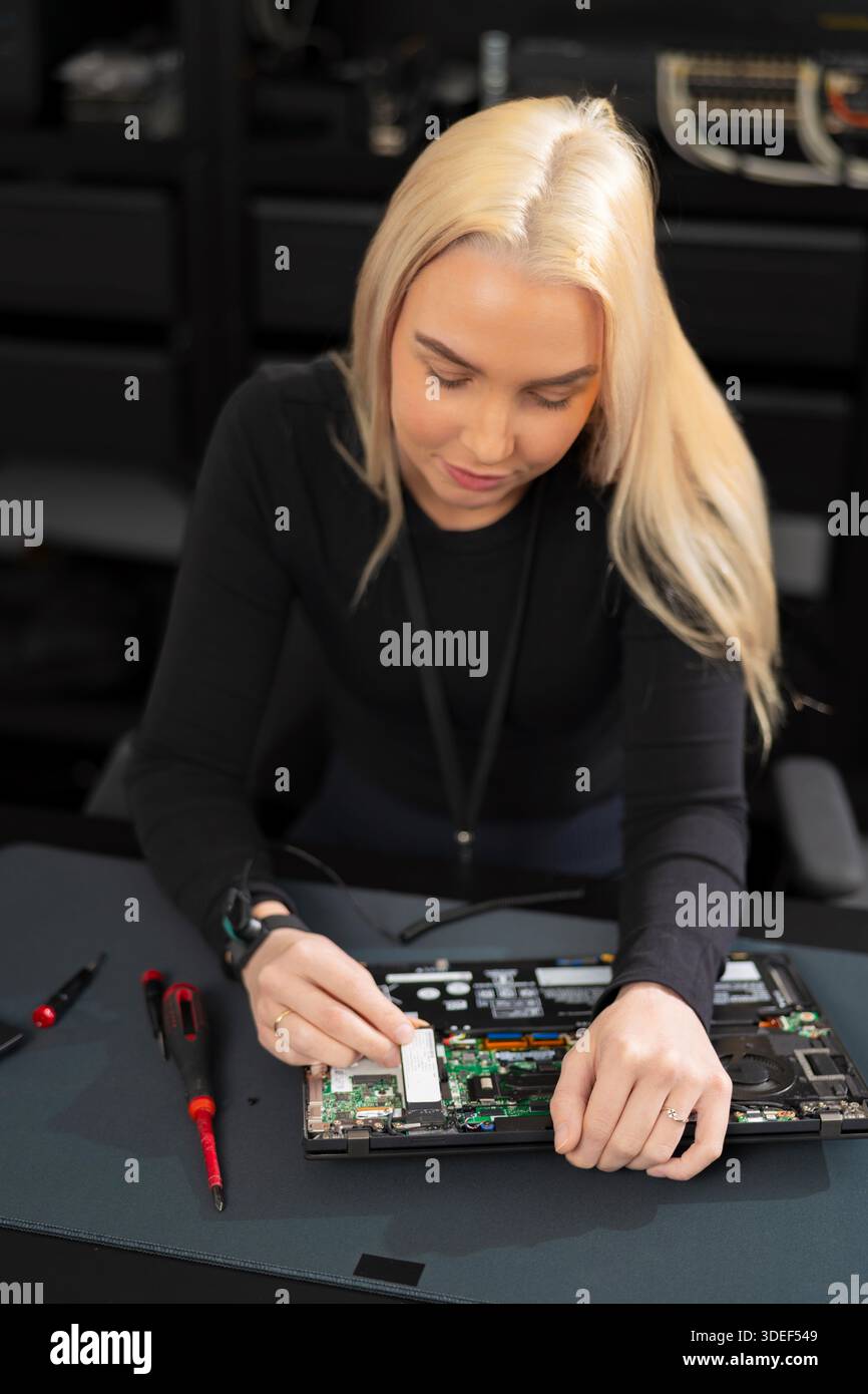 Eine IT-Technikerin arbeitet während der Reparatur und Aktualisierung in einer Werkstatt an der Hardware für Laptops Stockfoto