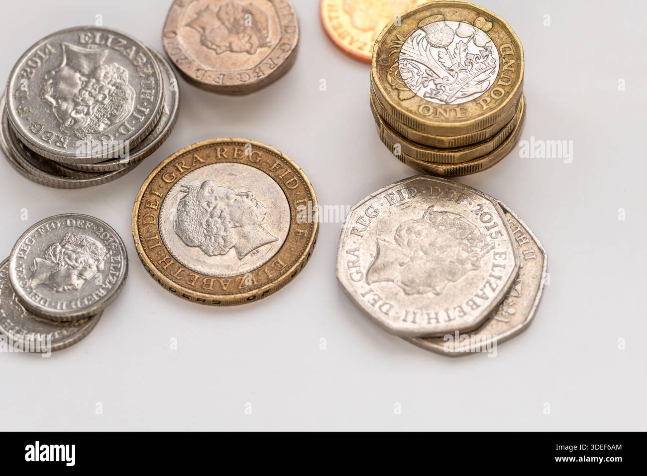 Eine Nahaufnahme von Stapeln verschiedener Pfund Sterling Münzen isoliert auf weiß. Stockfoto