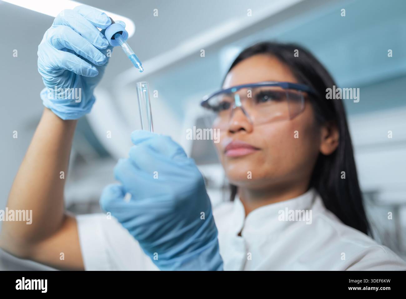 Eine professionelle asiatische Wissenschaftlerin arbeitet in einem modernen Labor, führt Tests durch und analysiert Proben mit Präzision. Stockfoto