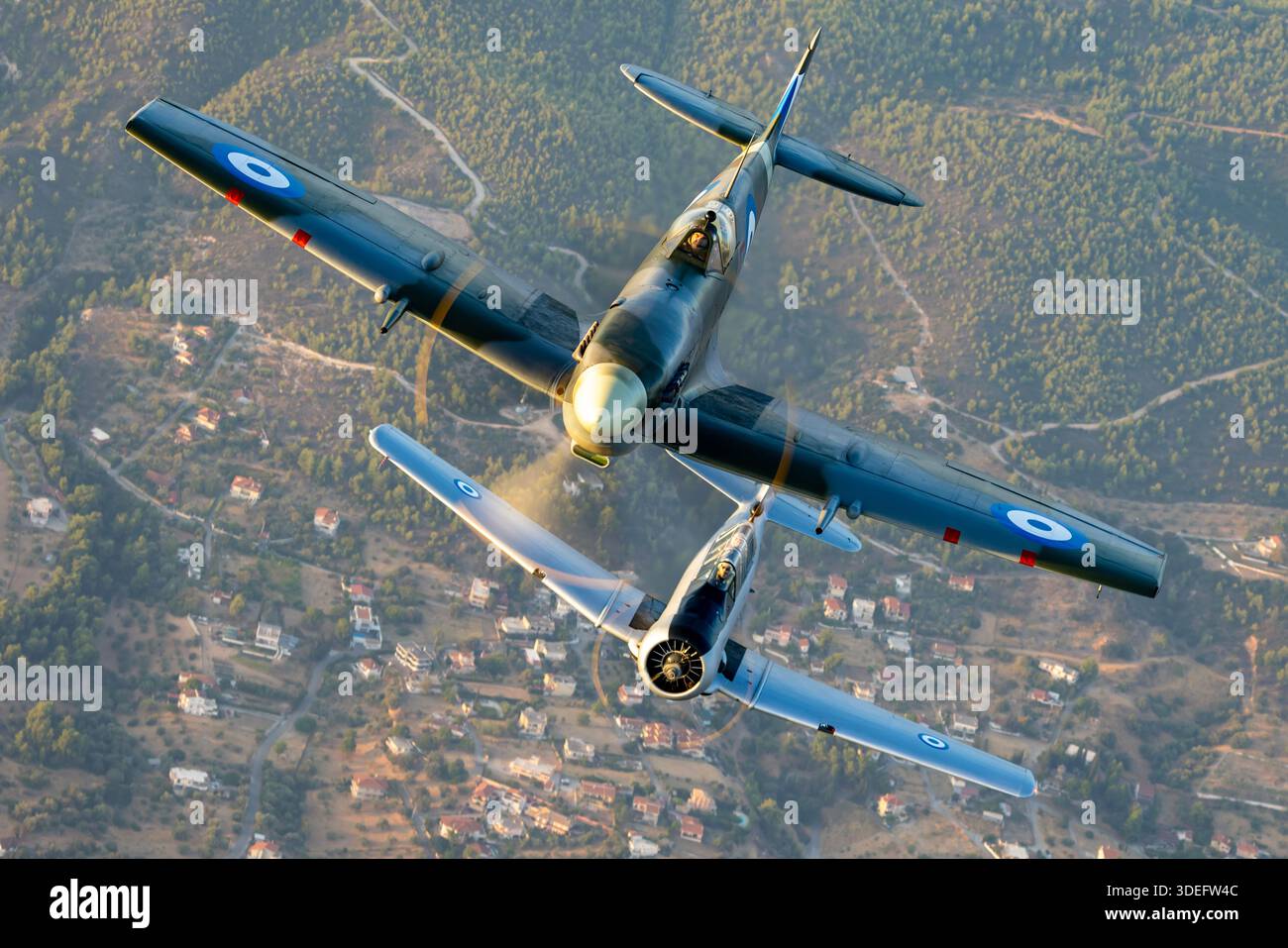 Luft-Luft-Formationsflug mit einem Supermarine Spitfire Mk IX MJ755 zusammen mit einem nordamerikanischen T-6G Texan 49-3424 während der Athens Flying Week 2025. Der Spitfire wird von einem Rolls-Royce Merlin 61 V12-Kolbenmotor angetrieben, während der T-6G einen Pratt & Whitney R-1340 Radialmotor verwendet. Beide propellergetriebenen Flugzeuge sind in koordinierter Form gezeigt, mit unterschiedlichen Flügeldesigns, Cockpit-Layouts und historischen Hellenic Air Force Markierungen im Flug. Stockfoto