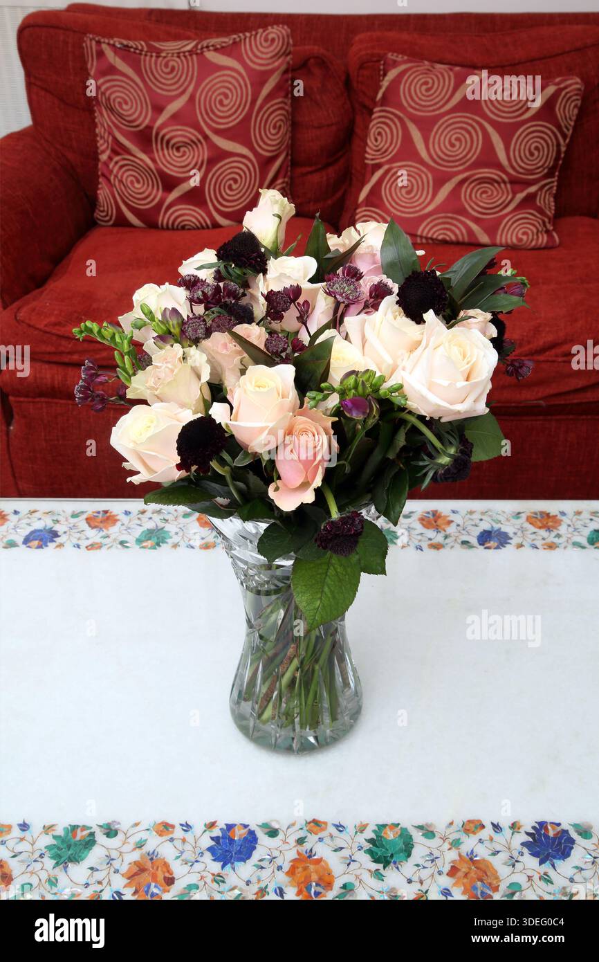 Blumenstrauß aus weißen und rosa Rosen in einer geschliffenen Kristallvase auf einem Marmortisch Stockfoto