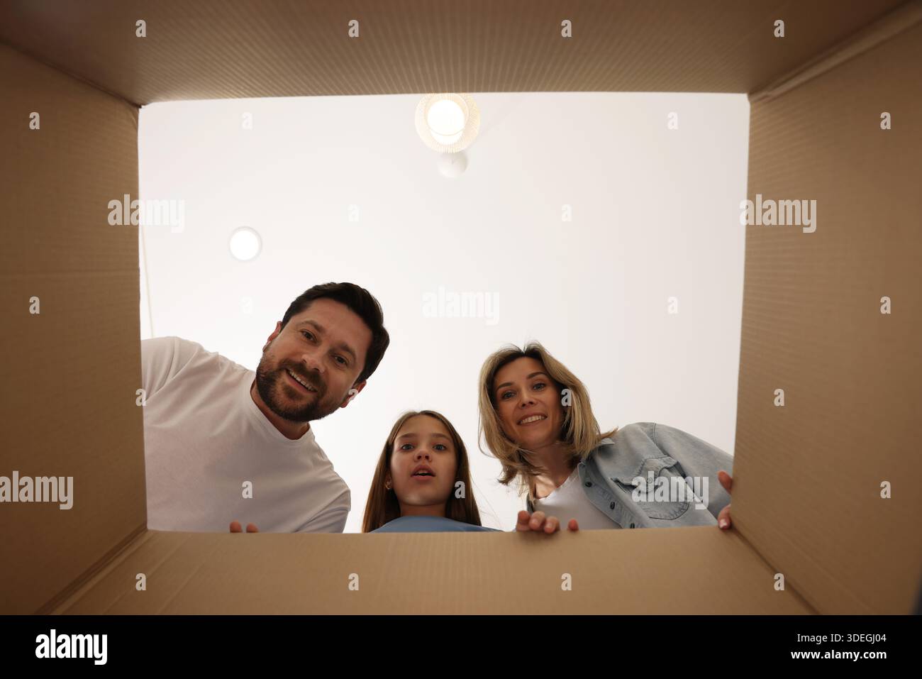 Begeisterte Familie, die in Kartons im Innenbereich schaut, Blick aus dem Inneren des Pakets Stockfoto