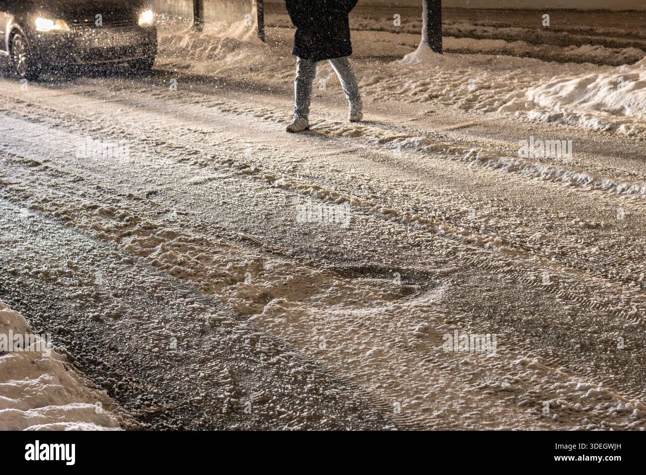 Der Mann überquert nachts die schneebedeckte Straße Stockfoto