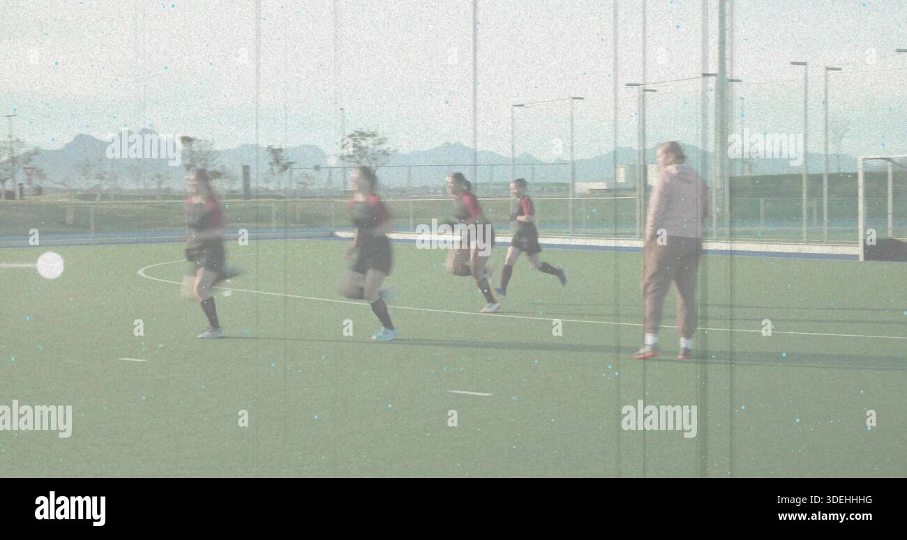 Vier weibliche Spieler in rot-dunklen Kits, die von links nach rechts auf dem Rasenfeld und im Torkäfig sprinten Stockfoto
