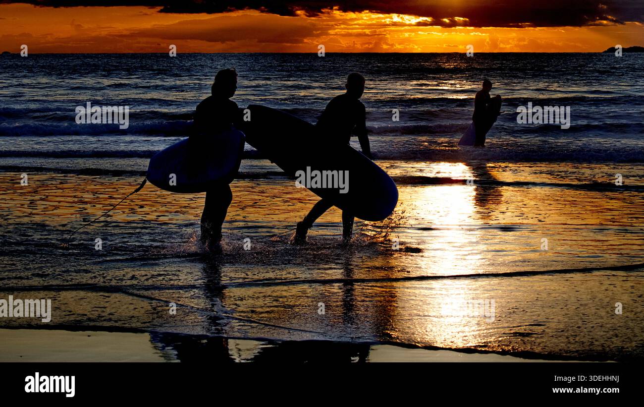 Drei Surfer bei Sonnenuntergang. Whitesands Beach, Whiitesands Bay, Pembrokeshire Wales, Großbritannien Stockfoto