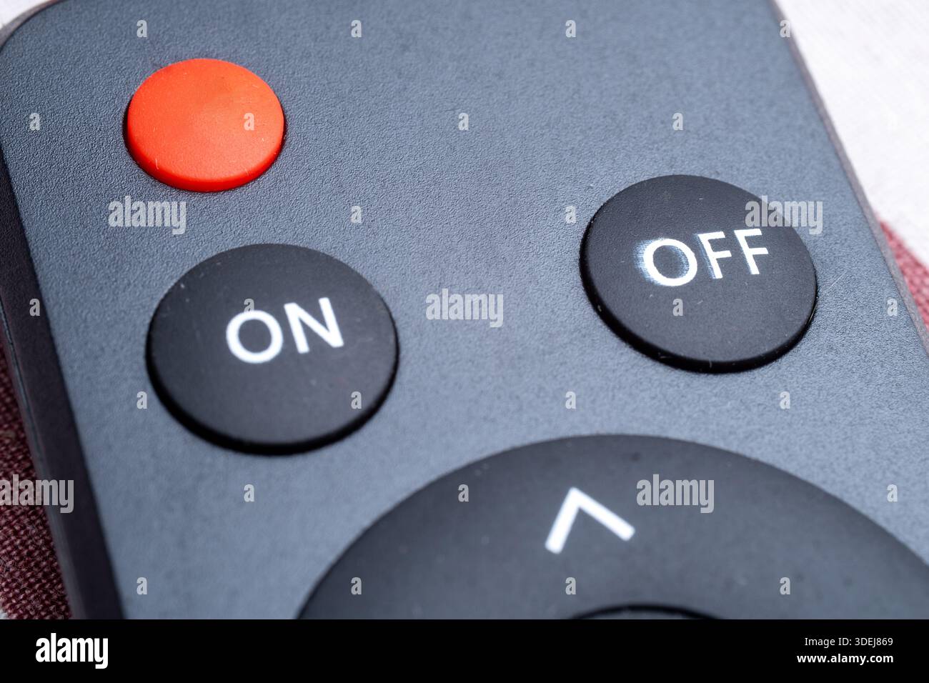 Nahaufnahme einer modernen Fernbedienungsoberfläche. Verfügt über einen markanten roten ein-/Ausschalter und klare weiße Etiketten auf schwarzer Oberfläche. Stockfoto