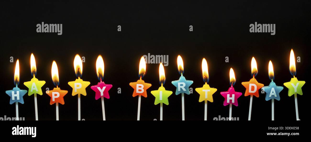 Brennende Kerzen mit den Worten Happy Birthday, brennende Kerzen in langer Reihe, isoliert auf dunkelschwarzem Hintergrund. Happy Birthday Karte Design Konzept Stockfoto