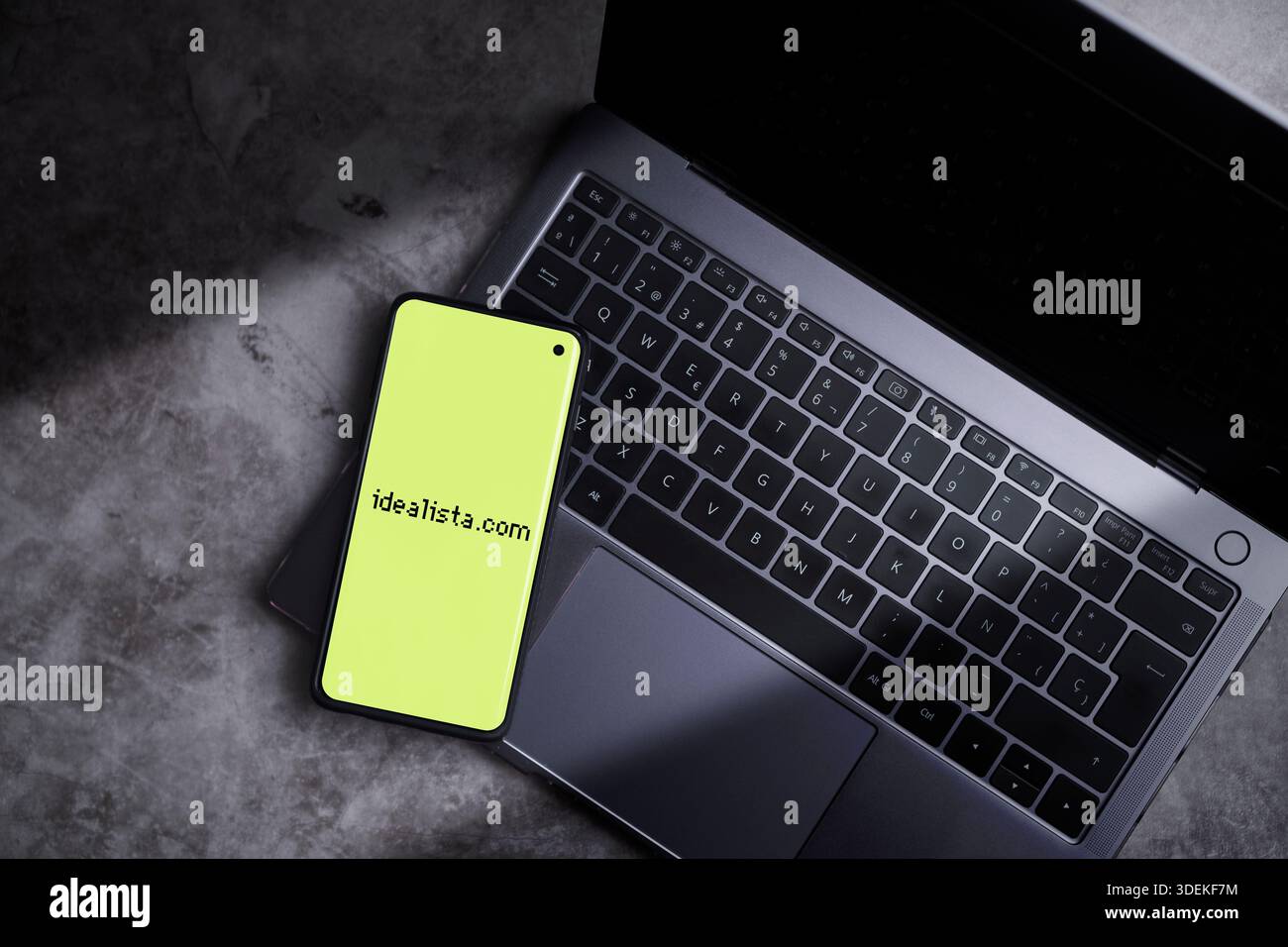 Smartphone auf der Laptop-Tastatur mit dem Idealista-Logo auf dem Bildschirm. Idealista ist ein spanisches Online-Unternehmen, das Immobiliendienstleistungen anbietet. Stockfoto