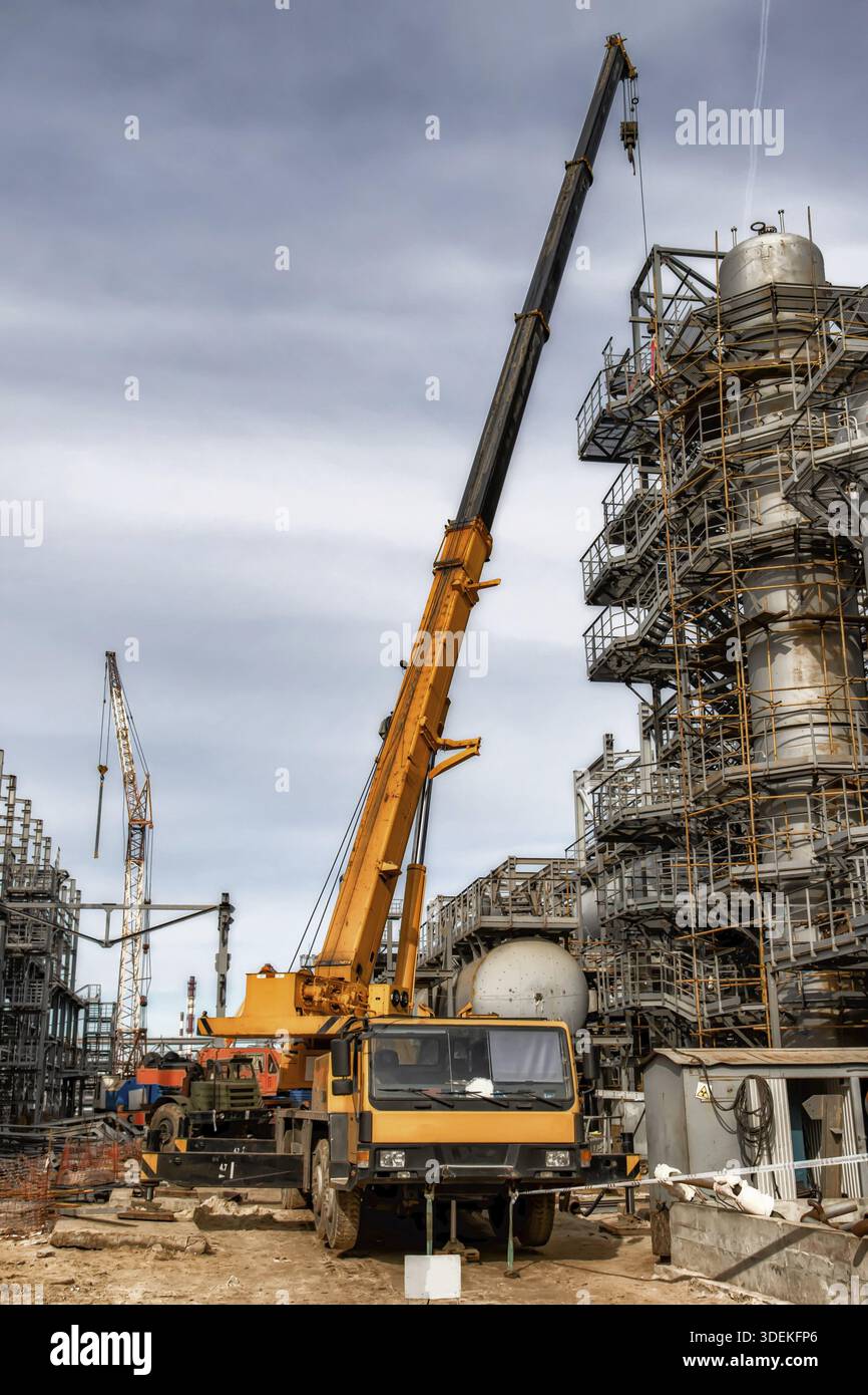 Auf der Baustelle einer Ölraffinerie steht ein großer gelber Autokran Stockfoto