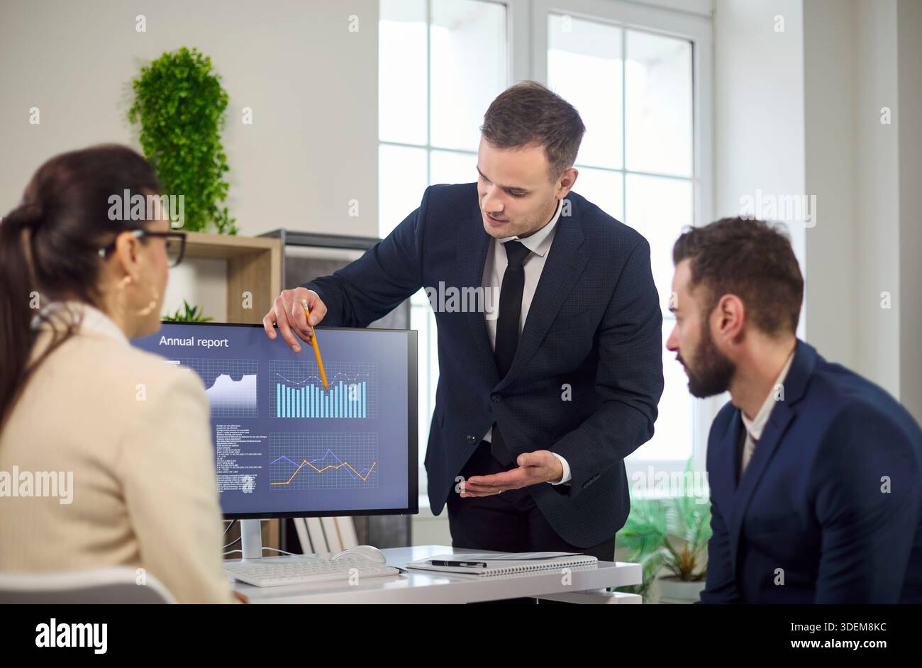 Manager, der dem Team während der Geschäftsbesprechung Dateneinblicke auf dem Monitor präsentiert Stockfoto