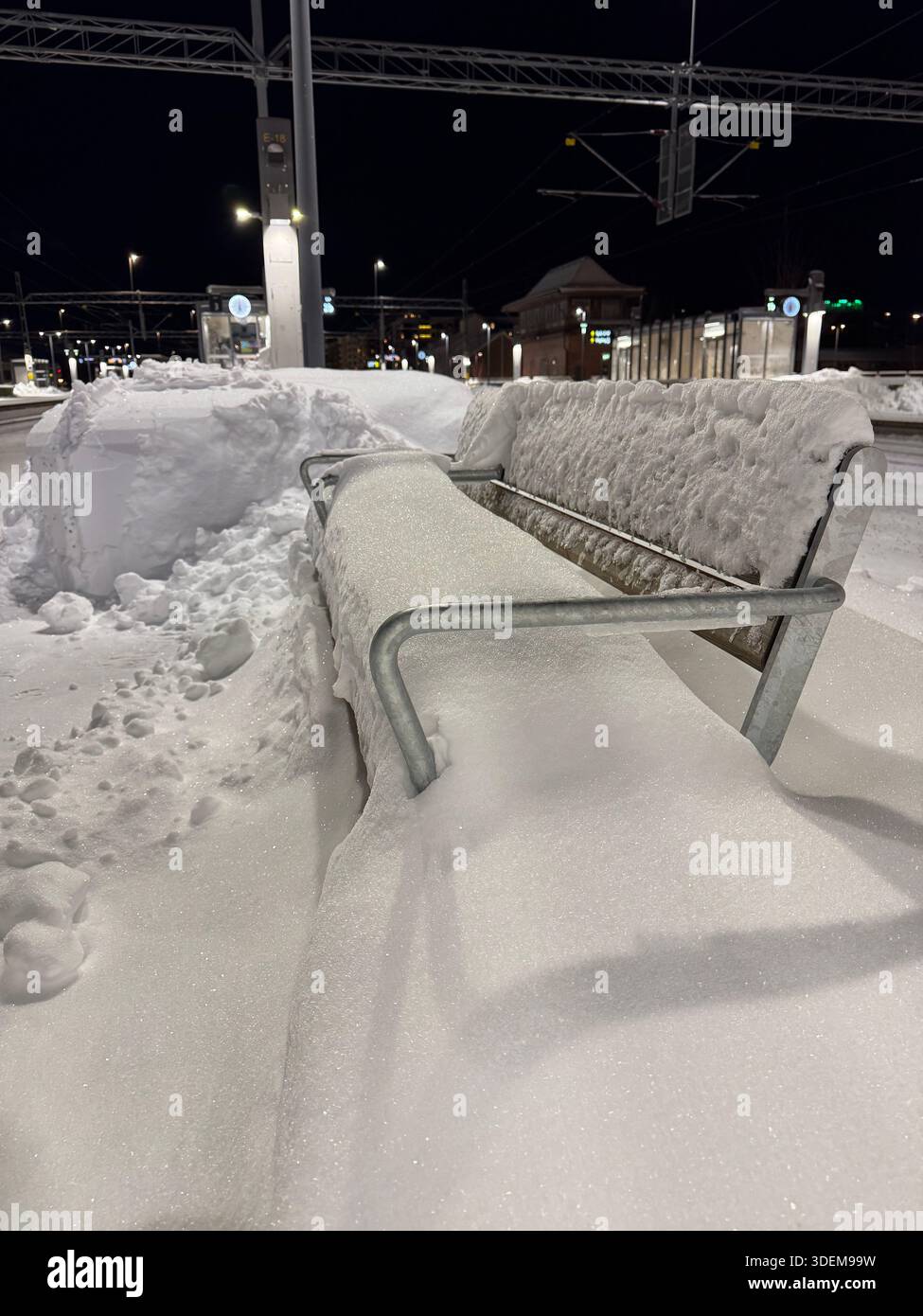 Schneebedeckte Bank am Hauptbahnhof Uppsala, Uppsala, Schweden. - Smartphone-aufgenommenes Stockfoto