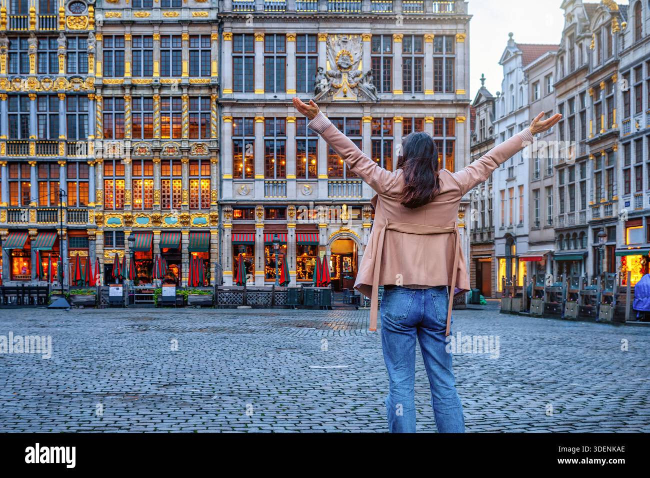 Eine glückliche Touristin auf einer Besichtigungstour durch Brüssel, Belgien, schaut sich die Architektur des Grand Place an, oder genannt Grote Markt Stockfoto