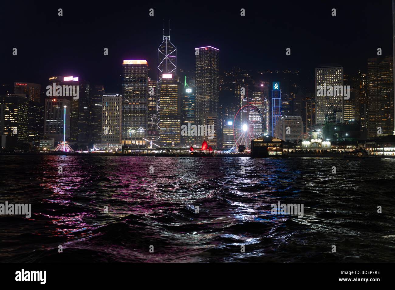 Skyline von Hongkong bei Nacht vom Victoria Harbour. Berühmte Gebäude wie der Bank of China Tower und das Riesenrad werden beleuchtet. Stockfoto
