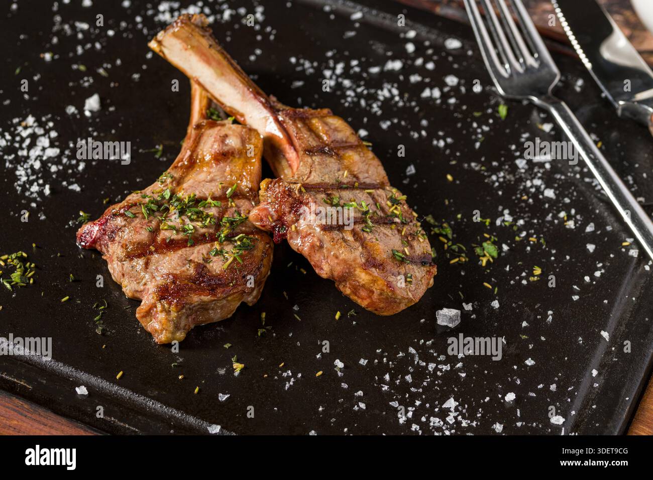 Gegrillte Lammkoteletts auf schwarzem Steinteller Stockfoto