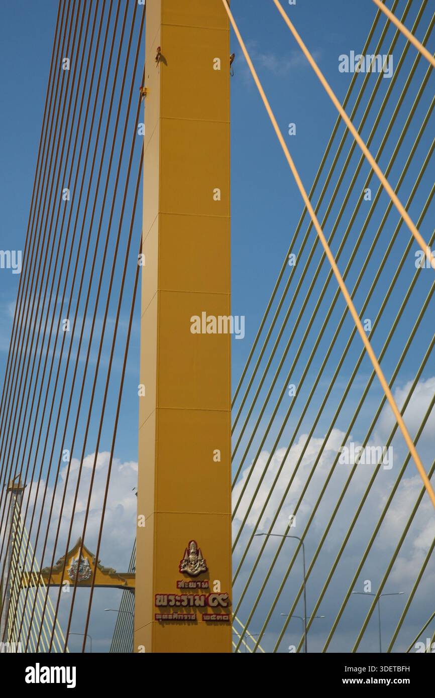 Aus nächster Nähe sehen Sie einen Turm und Kabelstege auf der Thotsamarachan-Brücke in Bangkok, von der angrenzenden Rama IX-Brücke mit Monsunwolken dahinter Stockfoto