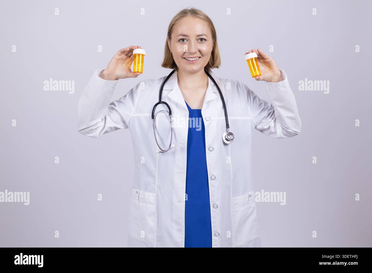 Weibliche Ärztin hält zwei gelbe Pillen-Flaschen Stockfoto