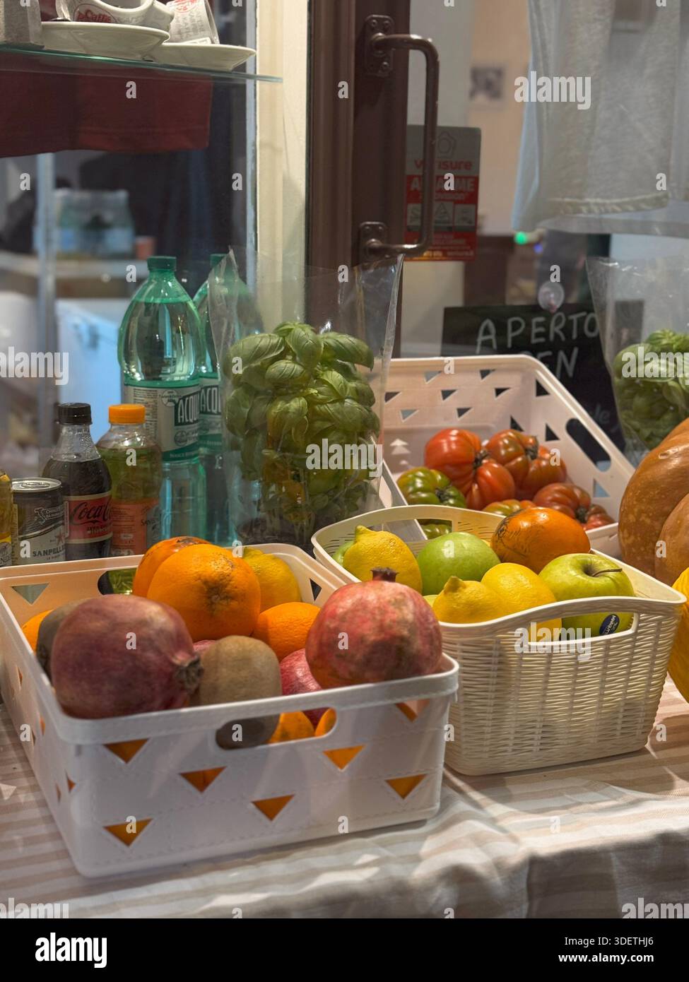 Verschiedene frische Früchte einschließlich Persimmons und Trauben, die in Kisten in einem römischen Lebensmittelgeschäft oder einem Lebensmittelgeschäft angeordnet werden. Stockfoto