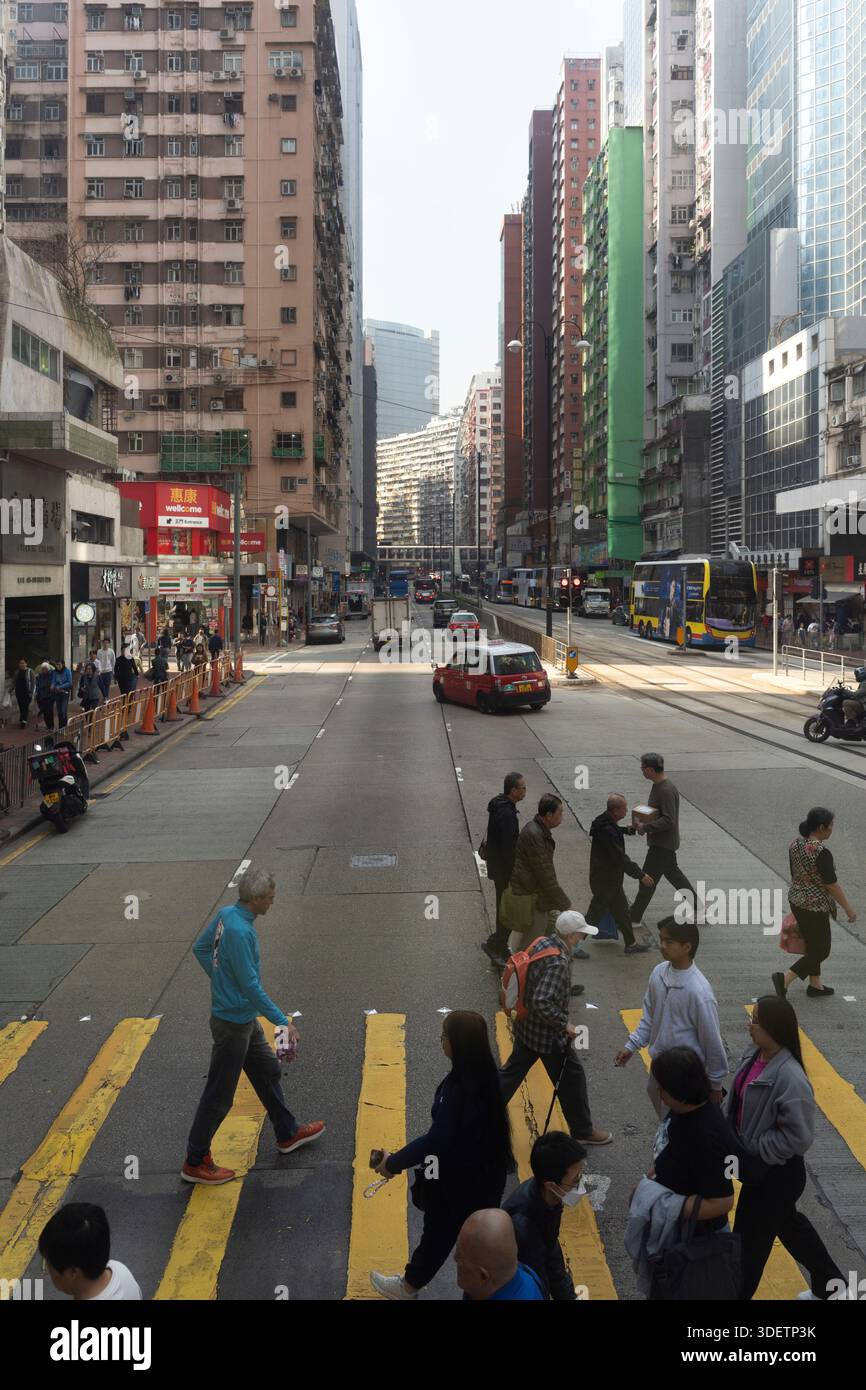 Die Menschen überqueren eine geschäftige Straße in Hongkong, in der Nähe des berühmten 7-Eleven North Point Stockfoto