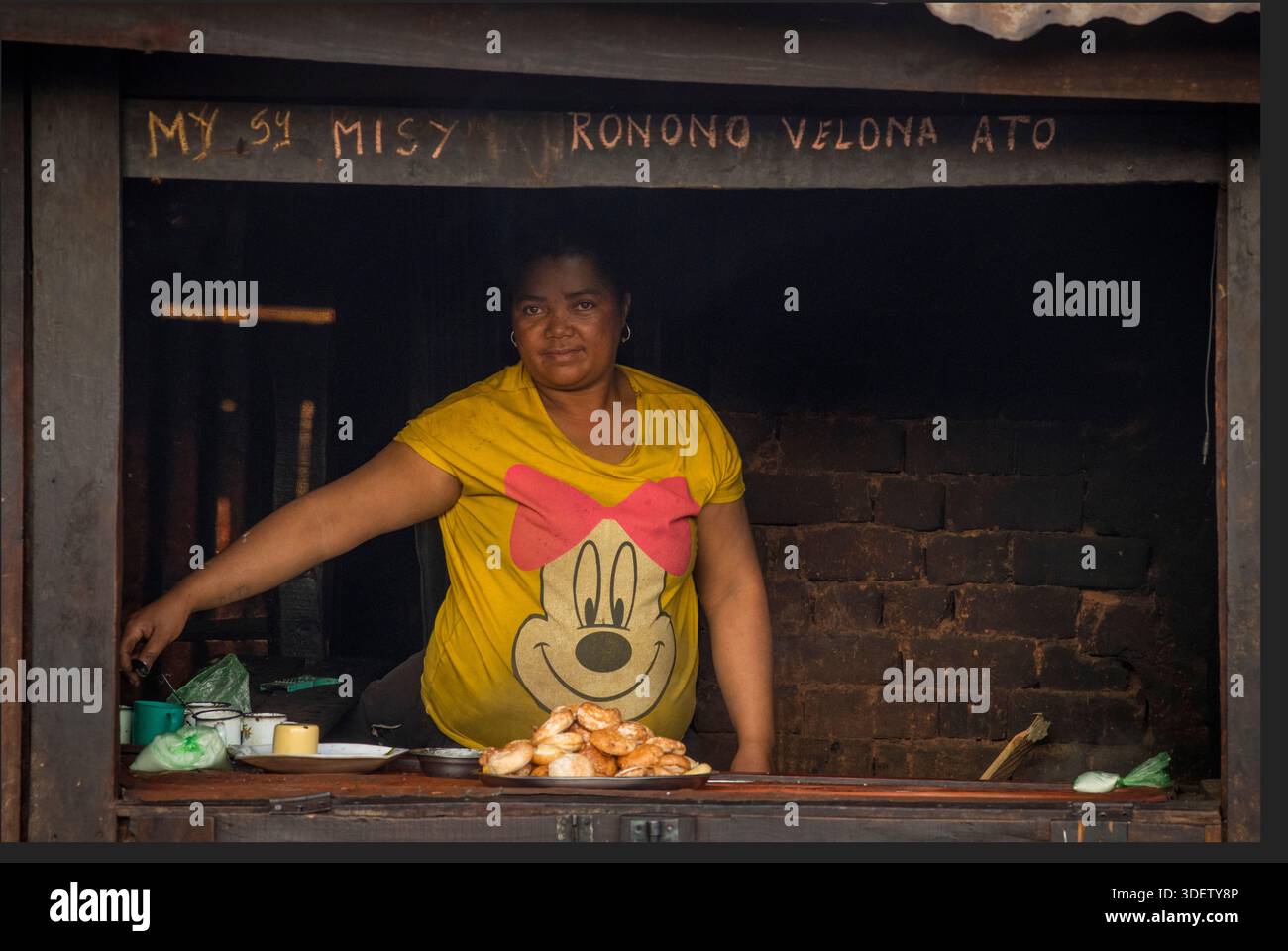 Eine madagassische Frau verkauft Snacks an ihrem Marktstand in Ambositra. Street Food ist ein integraler Bestandteil des madagassischen Lebens und der madagassischen Kultur, da es erschwingliche Mahlzeiten und eine primäre Einkommensquelle für viele Frauen in der informellen Wirtschaft bietet. Der madagassische Satz „MISY ronono velona ato“ Stockfoto