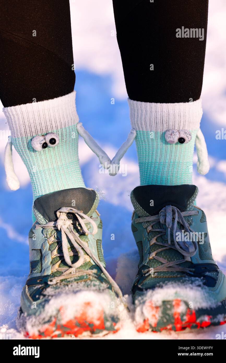 Verspielte Monster Socken mit Figuren, die Hände halten, und Laufschuhe im Winterschnee Stockfoto