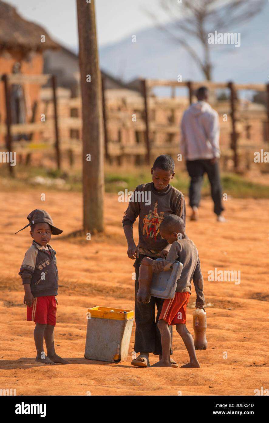 Kinder, die Behälter mit Flüssigkeiten verkaufen, Zebu Marktgelände, Ambalavao, Madagaskar. Im großen Viehhandel arbeiten Kinder oft als Wanderverkäufer, verkaufen lokale Säfte oder sogar medizinische Rindenaufgüsse an Hirten, die Hunderte von Kilometern zurückgelegt haben. Diese Szene zeigt die weitverbreitete Beteiligung madagassischer Jugendlicher im Dienstleistungssektor als Reaktion auf den starken wirtschaftlichen Druck. Diese Arbeit bietet Familien, die in extremer Armut leben, ein unmittelbares Einkommen, spiegelt aber auch die umfassenderen Herausforderungen in Bezug auf Kinderarbeit und den eingeschränkten Zugang zu formaler Bildung in ländlichen Regionen wider. Stockfoto
