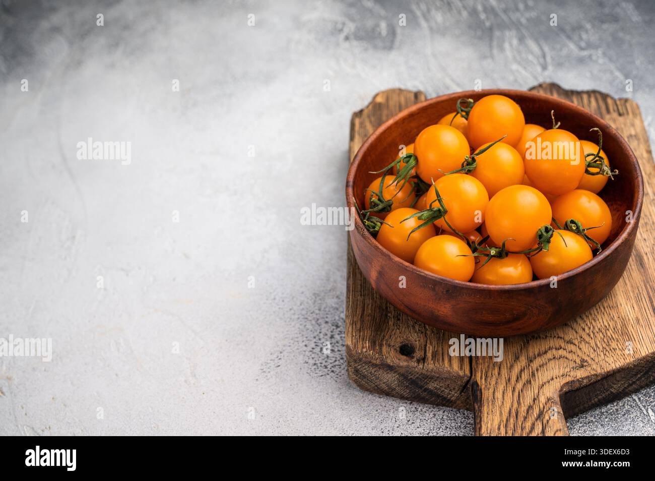 Frische kleine gelbe Kirschtomaten-Sortiment, Mini-Bio-Cocktail-Tomatenmischung. Grauer Hintergrund. Draufsicht. Stockfoto