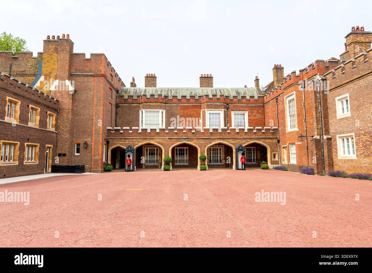 Blick auf den Innenhof des St. James’s Palace mit historischer Backsteinarchitektur und diensthabenden britischen königlichen Wachposten. Stockfoto