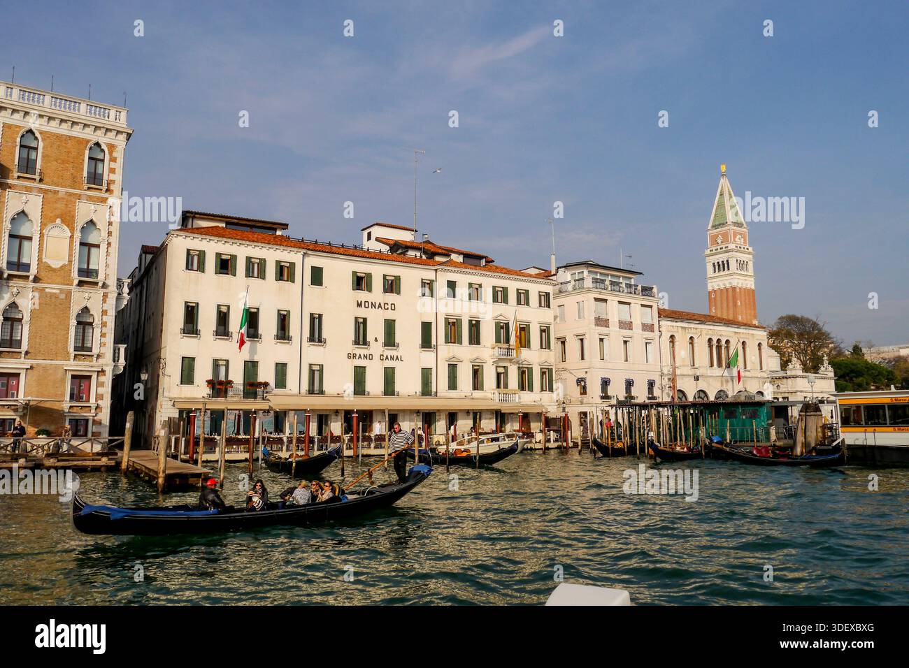 Hotel Monaco der Canal Grande in Venedig, Italien, mit einer Gondel im Vordergrund die Hauptwasserstraße der Stadt, gesäumt von historischen Palästen und mit Booten, zeigt die ikonische Architektur und das tägliche Leben der Lagunenstadt Venedig, Italien, eine historische Stadt auf Kanälen und Inseln in der Lagune von Venedig, berühmt für ihre Architektur, Wasserstraßen und zeitloses Kulturerbe. Stockfoto