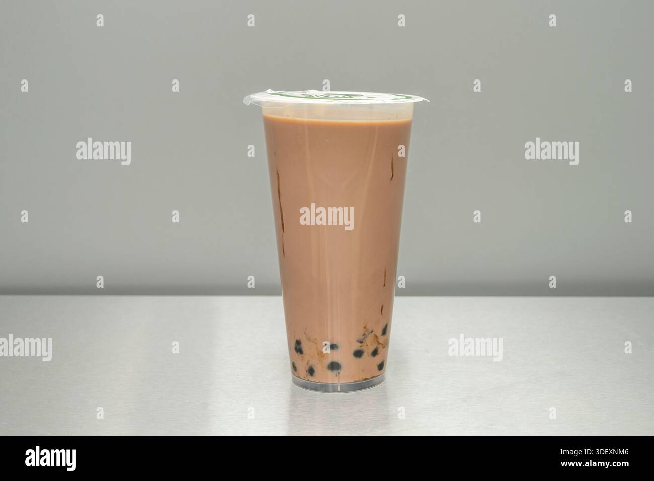 Ein dunkler Schokoladen-Bubble-Tee mit einem großzügigen Topping Schlagsahne und bestreuten Schokoladenspänen, neben dem Deckel, wo ein Loch für t geschnitten wurde Stockfoto