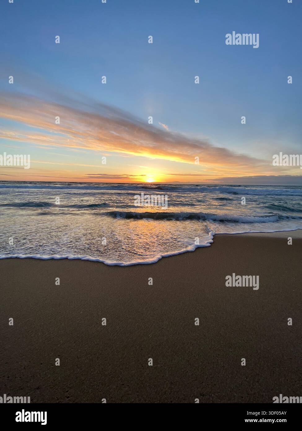 Meereswellen bei Sonnenaufgang, goldenes Licht reflektiert auf dem Wasser und bunte Wolken am Himmel - Smartphone-aufgenommenes Stockfoto
