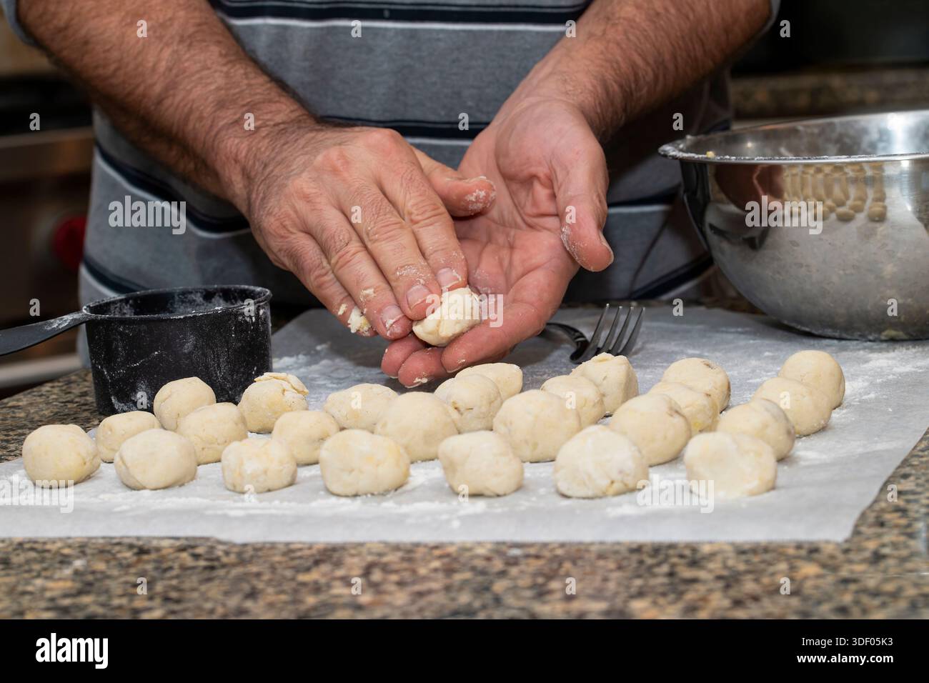 Der Mann rollt Bälle aus handgemachtem Gnocchi-Teig aus Stockfoto