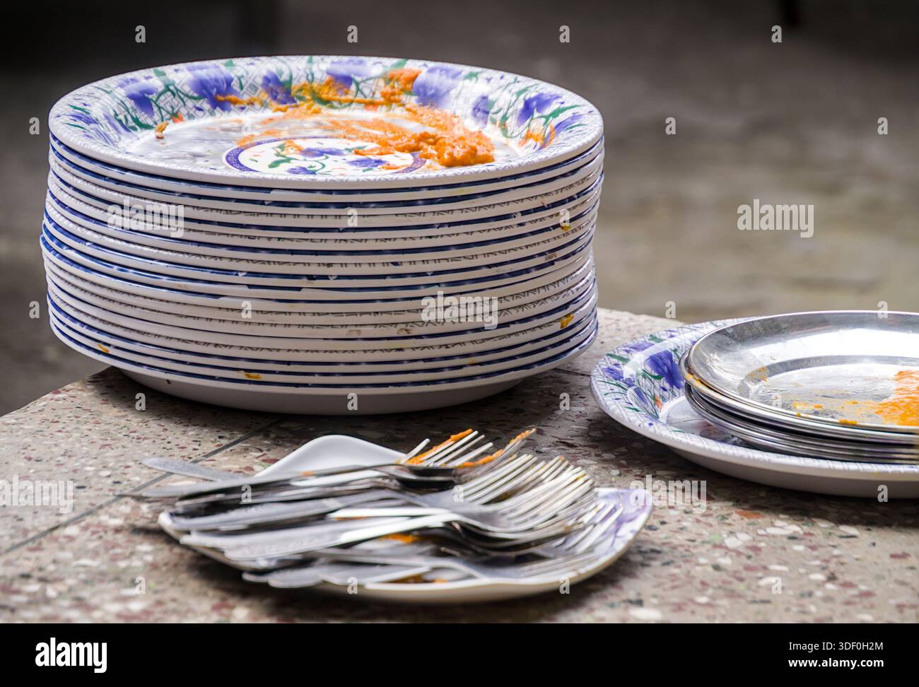 Ein Stapel schmutziger Teller und Besteck mit Resten, die nach dem Essen unordentlich waren und ungewaschenes Geschirr zeigen. Stockfoto