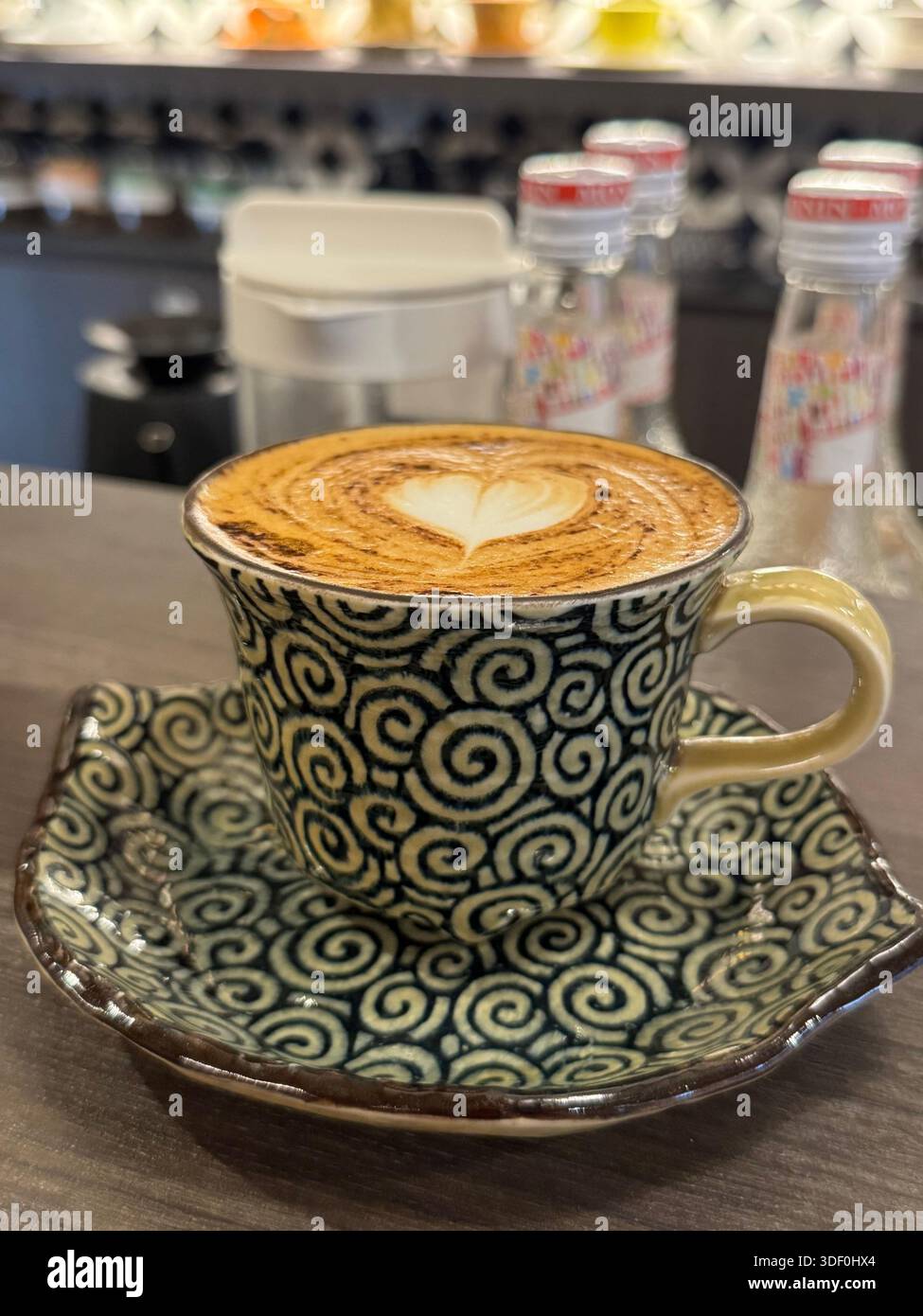 Cappuccino mit herzförmiger Latte Art, serviert in einer Tasse mit Spiralmuster - ein perfektes Café Momen Stockfoto