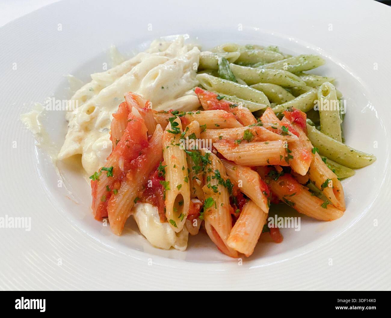 Eine Mischung aus Penne-Pasta, die in verschiedenen Saucen (Pesto, alfredo, Marinara) gekocht wird Stockfoto